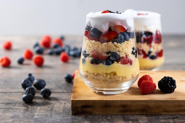 Trifle dessert with berries and cream on wooden table