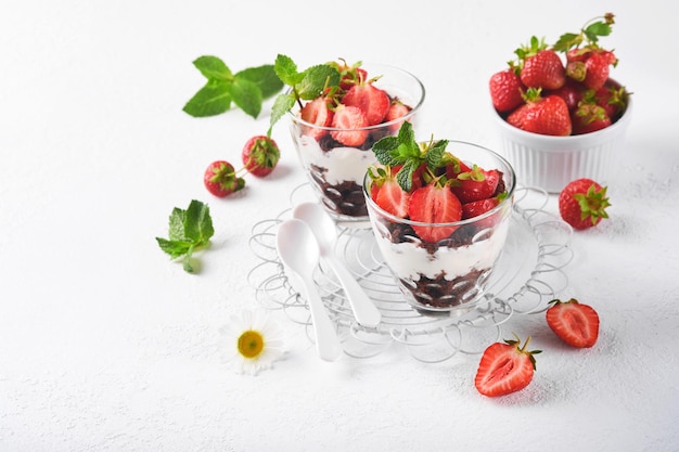 Trifles Brownies fresh strawberry and mascarpone cream servered in layers on glass on white background Portion desserts No baked brownie cheesecake with fresh berries in a glass