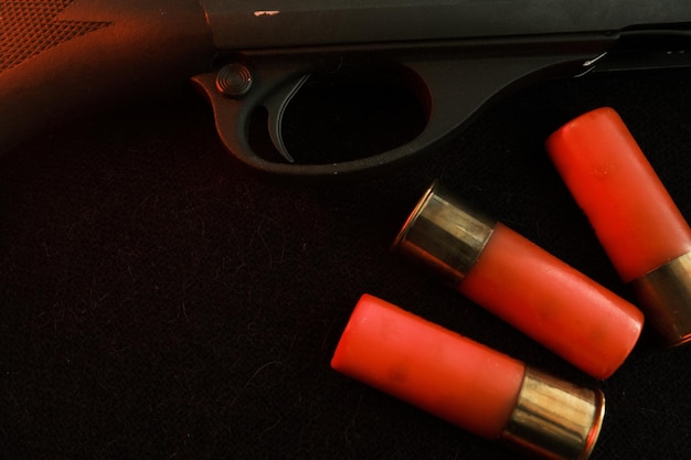 Trigger of a rifle on black background with red lightning with Shotgun shells on a black surface Ammunition for 12 gauge smoothbore weapons Hunting ammunition Dark background