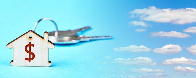 Trinket with the keys to the apartment on the blue background with sky and clouds