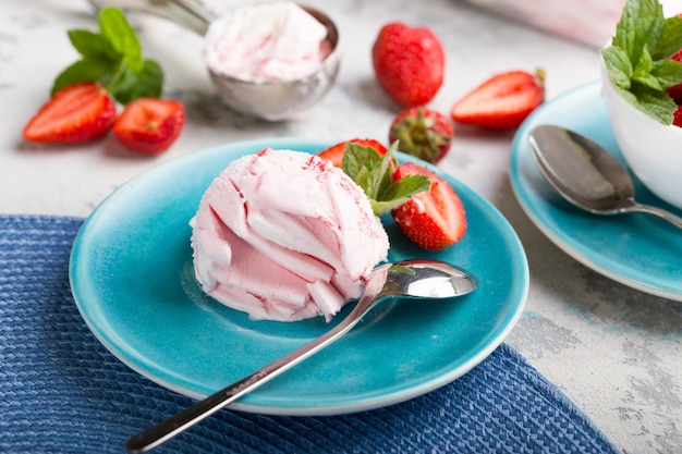 Trio of tasty vanilla and strawberry flavored frozen dessert ice cream in a  bowl with mint on a stone