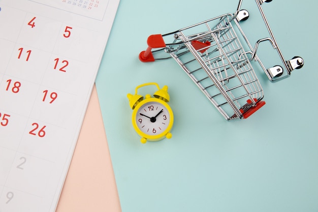 Trolley with yellow alarm clock , shopping online concept