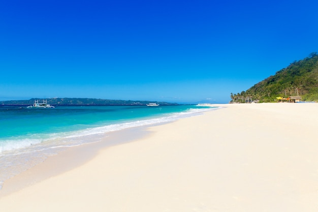 Tropical beach and beautiful sea with boats. Blue sky with clouds in the background.