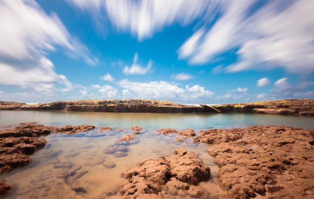 Tropical beach landscape with coconut trees and rocks long exposure.