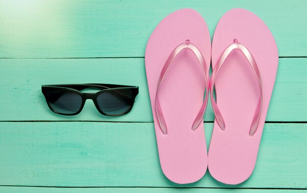 Tropical beach lifestyle. Flip flops and sunglasses on blue wooden background. Summer background. Top view