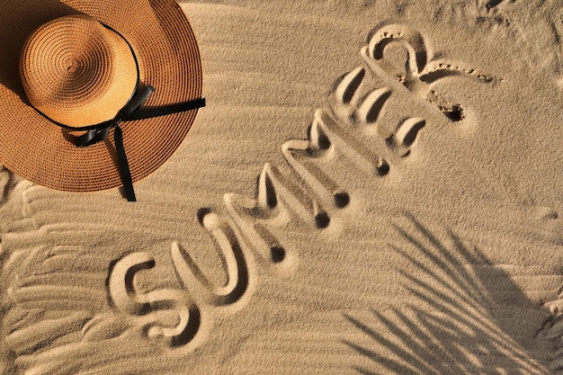 Tropical beach sand with shadows of coconut palm tree leaves and hat travel and vacations concept ba