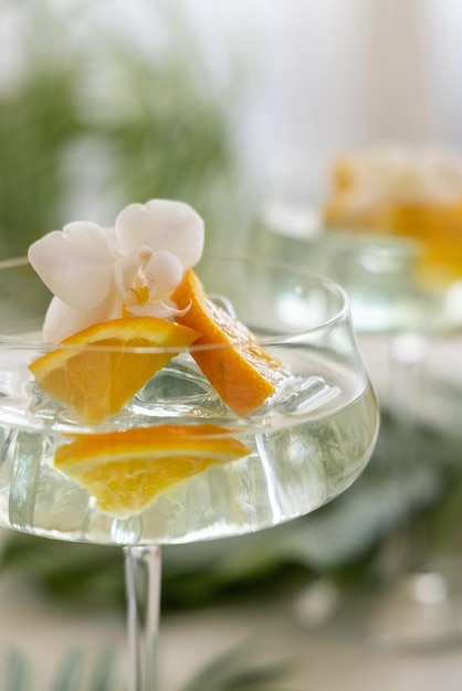 Tropical Cocktail in a glass decorated with slices of orange and orchid flower close up