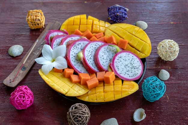 Tropical fruits assortment on a plate, close up. Many colorful ripe tropical fruits background. Mango, papaya and pitahaya