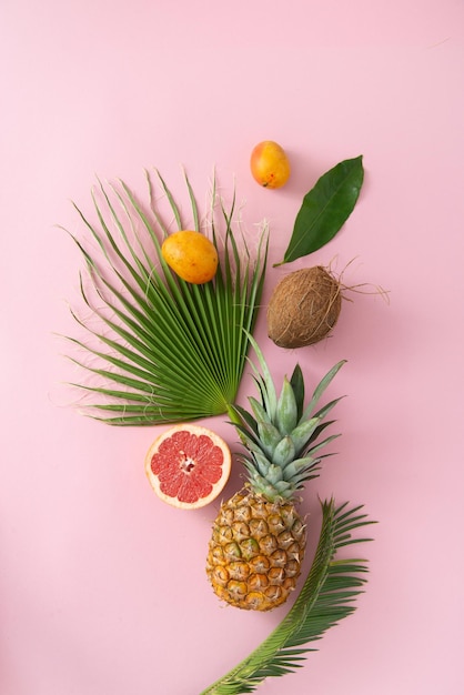 tropical fruits and leaves on a pink background top view