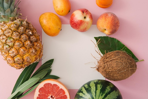 tropical fruits and leaves on a pink background top view