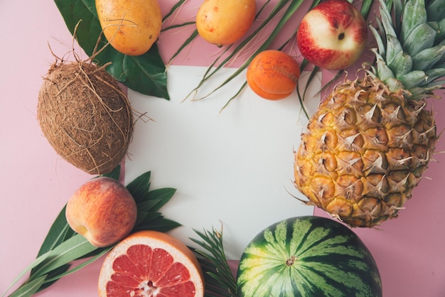 tropical fruits and leaves on a pink background top view