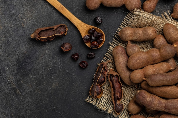 Tropical fruits Tamarindo beans in shell on a brown butchers block on a dark background healthy fruit banner menu recipe place for text top view