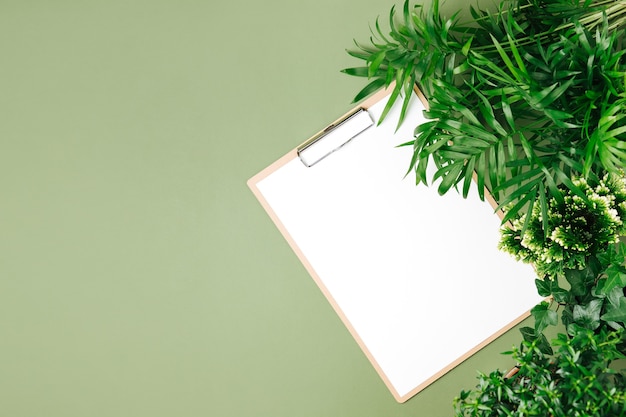 Tropical leaves and clipboard on light green background mockup, top view