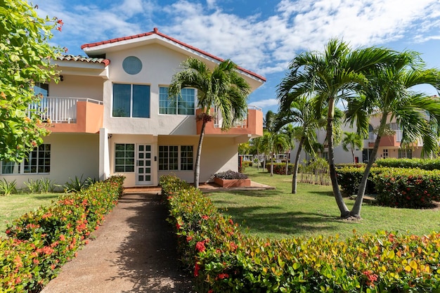 Tropical Luxury House With Palm Trees and Green Grass Beautiful backyard with a garden in front of a twostory house landscape design