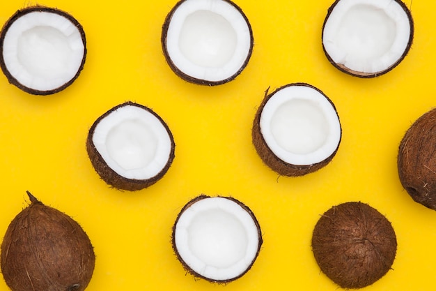 Tropical summer coconut background half and whole coconuts on a yellow background