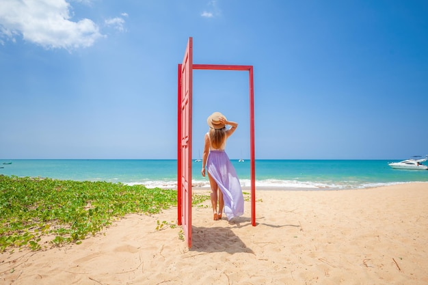 Tropical travel vacation traveler woman in red door on beach to turquoise sea