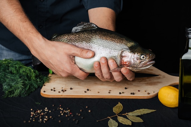 Trout in hands of a man on background of kitchen. Big fresh fish with chef