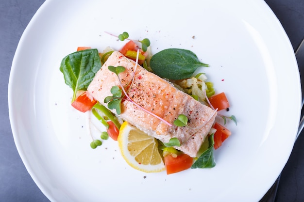 Trout (salmon) with vegetables, lemon and microgreens, cooked by the confit method. Traditional French dish. Step by step. Top view.