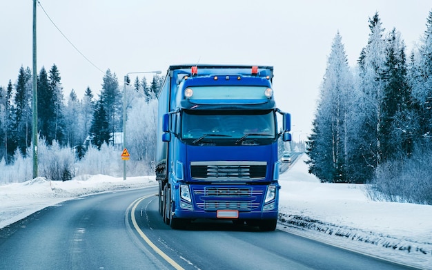 Truck in snow winter road of Finland. Trucker in highway. Lorry doing logistics work. Semi trailer with driver. Big cargo car drive. Freight delivery. Transport export industry. Container with goods