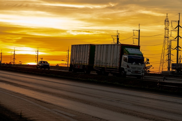 Truck with Cargo driving on road transportation highway at sunset in summer