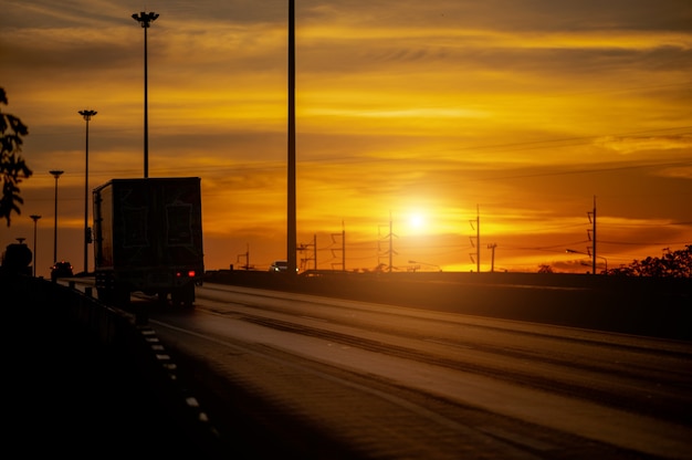 Truck with Cargo driving on road transportation highway at sunset in summer