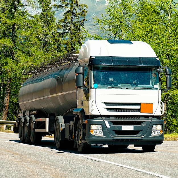 Truck with liquid or oil storage in road or highway of Switzerland. Lorry with service tanker cistern at logistics work. Semi trailer tank. Cargo car drive. Freight delivery. Transport export industry