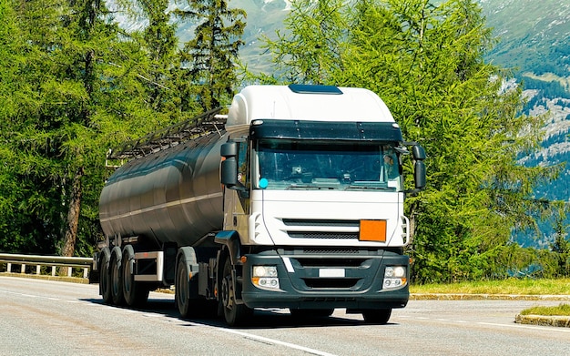 Truck with liquid or oil storage in road or highway of Switzerland. Lorry with service tanker cistern at logistics work. Semi trailer tank. Cargo car drive. Freight delivery. Transport export industry