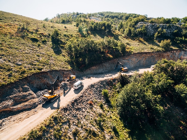 Trucks drive along the road to the sand pit against the backdrop of greenery