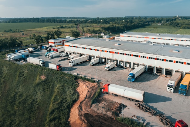 Trucks with trailers are loaded and unloaded in the cargo terminal in the morning aerial shot contai...