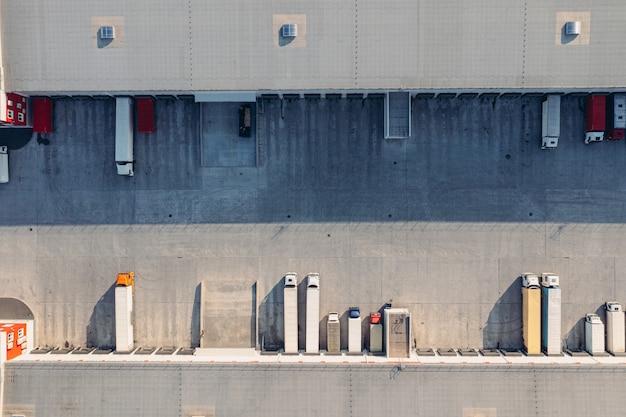 Trucks with trailers wait for the loading of goods for transportation in the loading warehouse aeria...