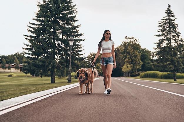 True friend. Full length of beautiful young woman walking with her dog while spending time outdoors