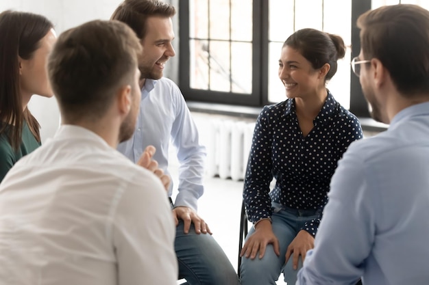 Photo trust relations friendly smiling diverse people business team sitting in circle listening to indian woman leader trainer exchanging opinions on informal meeting taking part in group therapy session