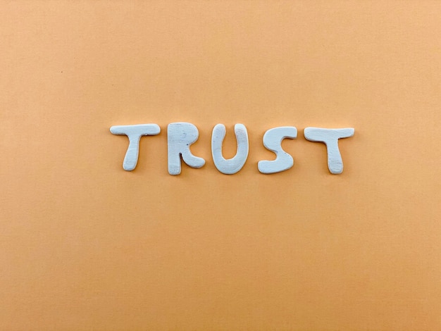 Photo trust word composed with wooden letters over orange color