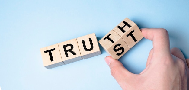 Truth instead of trust. Hand turns dice and changes the word Trust to Truth.