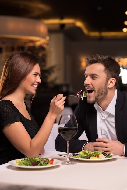 Try it! Beautiful young couple feeding each other and smiling while spending time at the restaurant