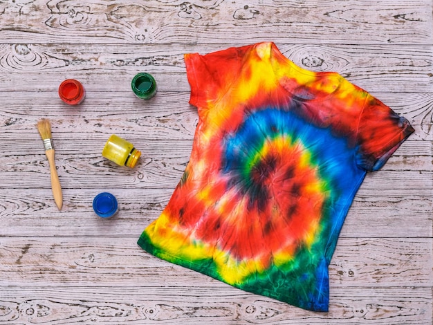 Tshirt decorated with a spiral tie dye style on a wooden background Flat lay