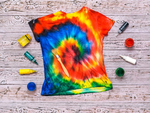 Tshirt painted in the style of tie dye with colors on a wooden background Flat lay