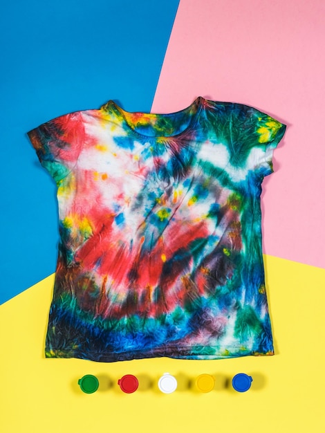 Tshirt in tie dye style and paint on a threecolor background Flat lay