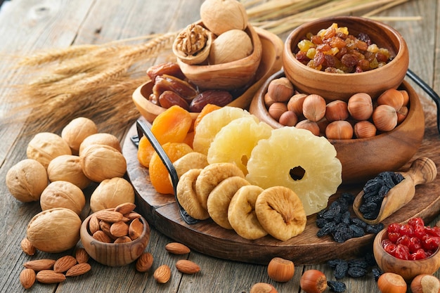 Tu Bishvat celebration concept Mix of dry fruits and nuts almonds hazelnuts walnuts apricots prunes cherries raisins dates apples figs over wooden table Jewish holiday new year of trees