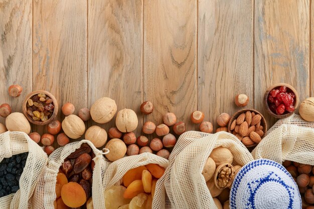 Tu Bishvat celebration concept Mix of dry fruits and nuts almonds hazelnuts walnuts apricots prunes cherries raisins dates apples figs over wooden table Jewish holiday new year of trees