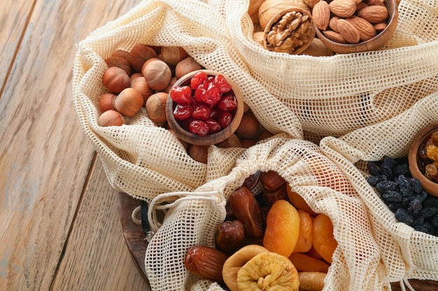 Tu Bishvat celebration concept Mix of dry fruits and nuts almonds hazelnuts walnuts apricots prunes cherries raisins dates apples figs over wooden table Jewish holiday new year of trees