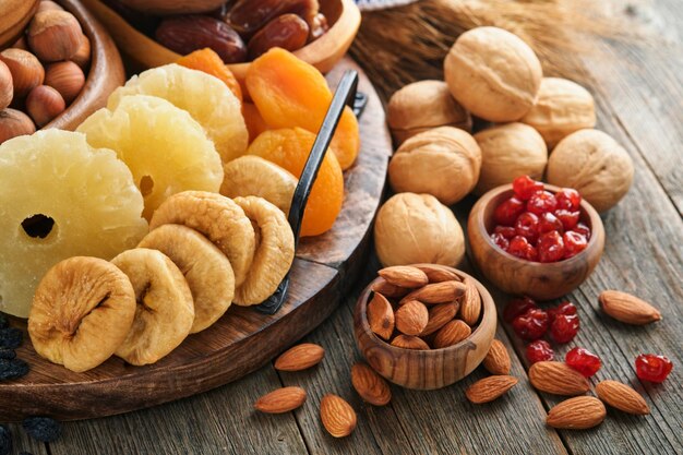 Tu Bishvat celebration concept Mix of dry fruits and nuts almonds hazelnuts walnuts apricots prunes cherries raisins dates apples figs over wooden table Jewish holiday new year of trees