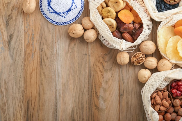 Tu Bishvat celebration concept Mix of dry fruits and nuts almonds hazelnuts walnuts apricots prunes cherries raisins dates apples figs over wooden table Jewish holiday new year of trees