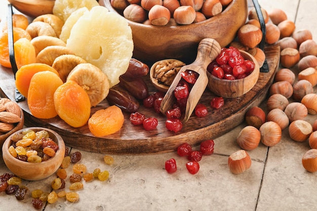 Tu Bishvat celebration concept Mix of dry fruits and nuts almonds hazelnuts walnuts apricots prunes cherries raisins dates apples figs over wooden table Jewish holiday new year of trees