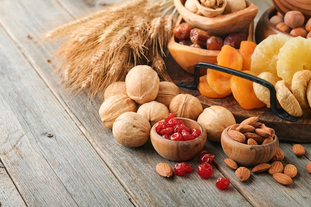 Tu Bishvat celebration concept Mix of dry fruits and nuts almonds hazelnuts walnuts apricots prunes cherries raisins dates apples figs over wooden table Jewish holiday new year of trees