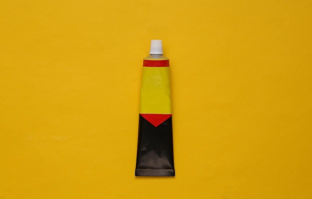 Tube of glue on a yellow background Top view