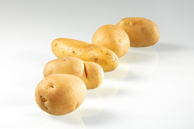 Tubers of young potatoes lie in a row on a white background