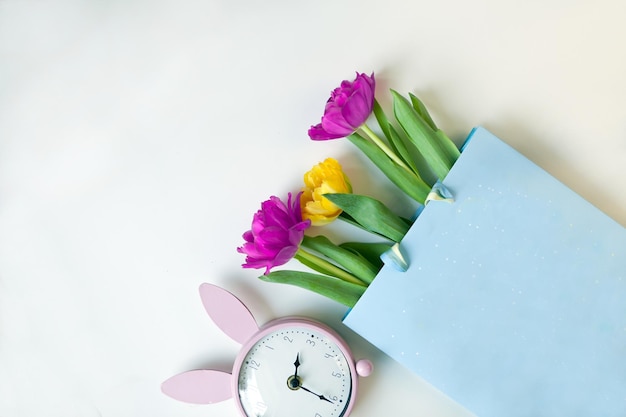 Tulip flowers gift paper and pink bunny clock in flat lay style greeting for womens or mothers day