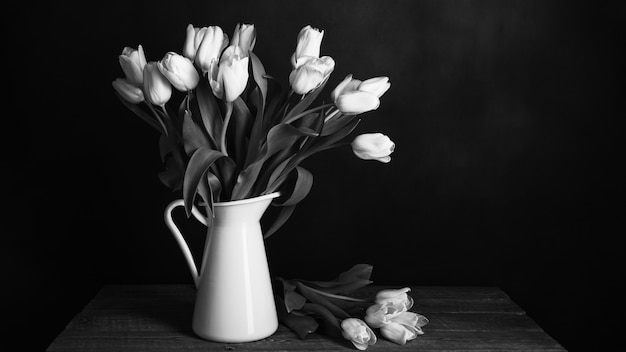 Tulips in a jug on dark background in black and white