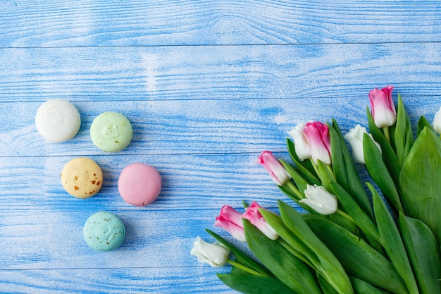 Tulips with macaroons on blue wooden background. rustic tulips.